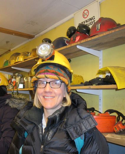 Figure 6. The author in the “tool room” of former mine 3, now a tourist destination. This room includes many of the different kinds of tools Longyearbyen miners have used over the past century. All tour attendees were given hard hats with headlamps before we descended into the mine. Later, some attendees donned lompen. Photo by the author.